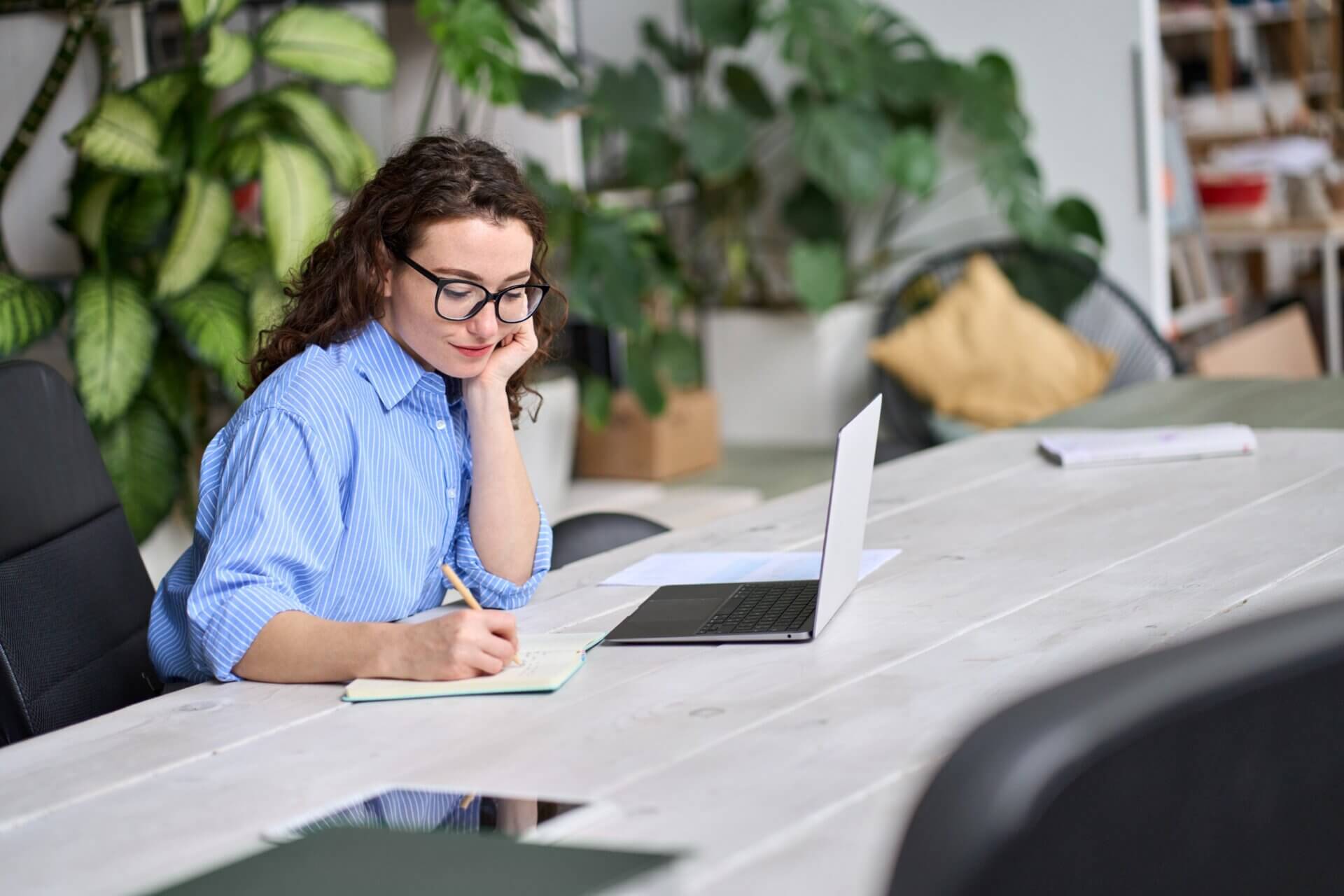 Mujer con gafas escribe en libreta oficina en casa