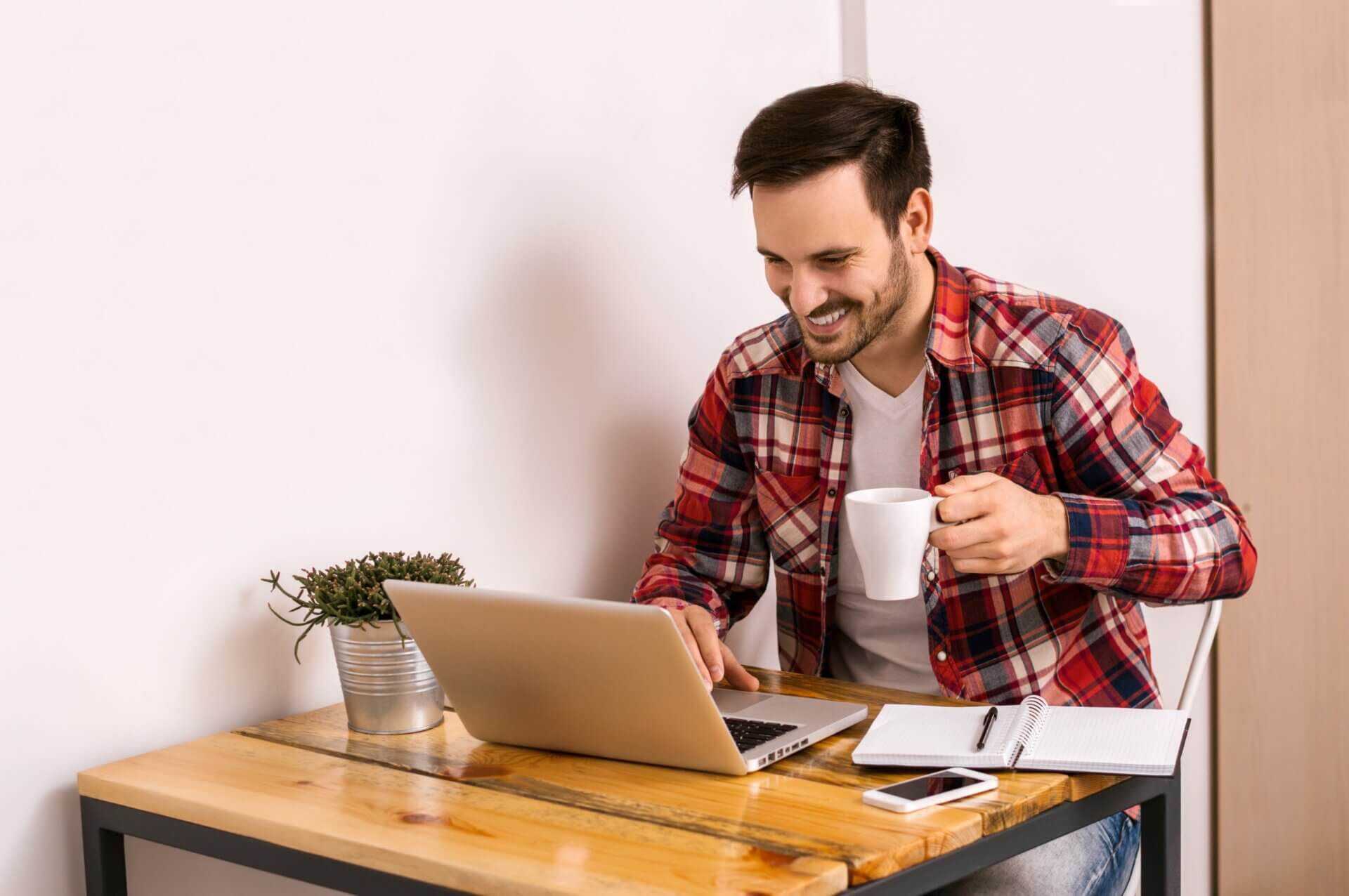 Hombre bebe café mientras trabaja en el ordenador