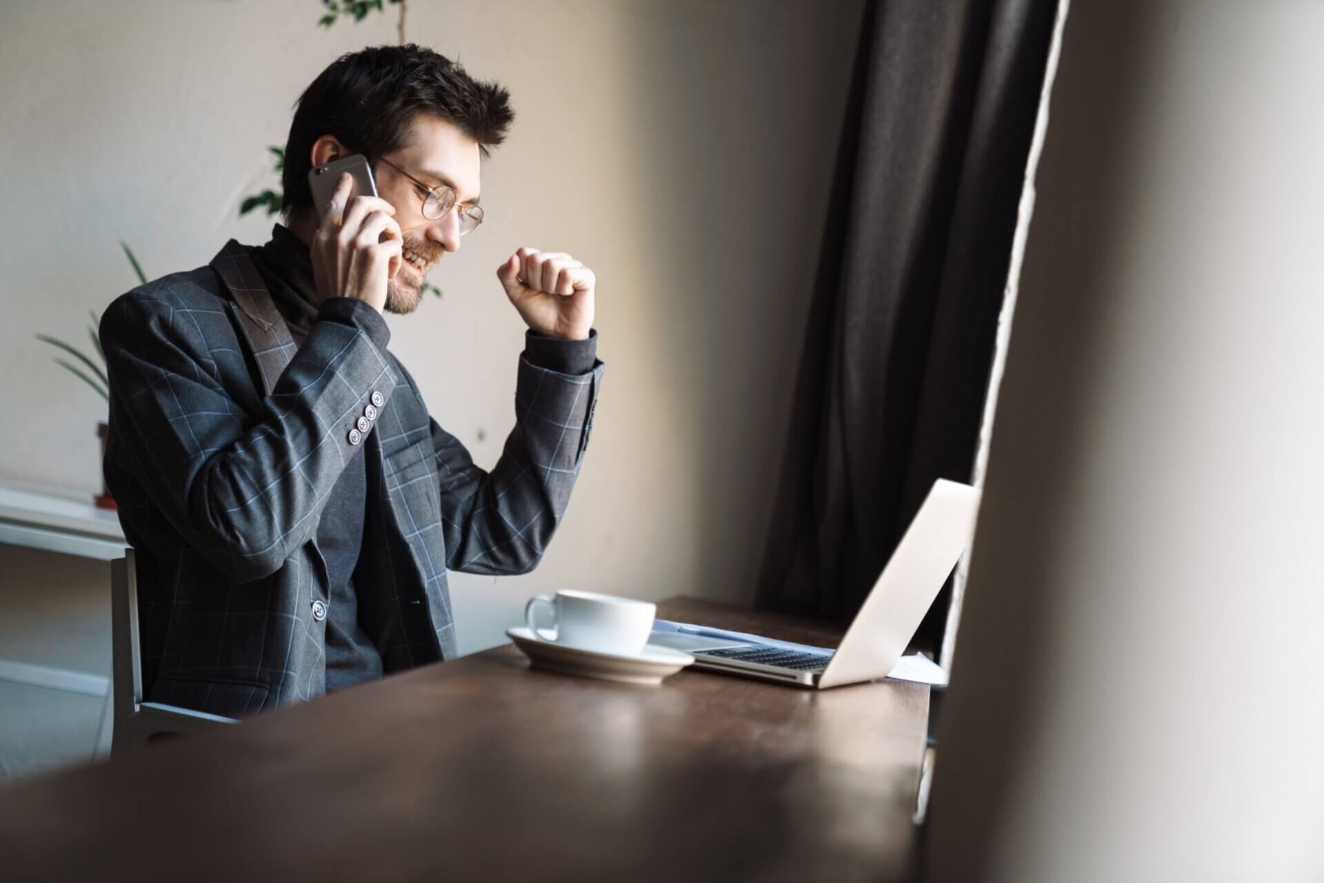 Hombre feliz habla por teléfono mientras trabaja