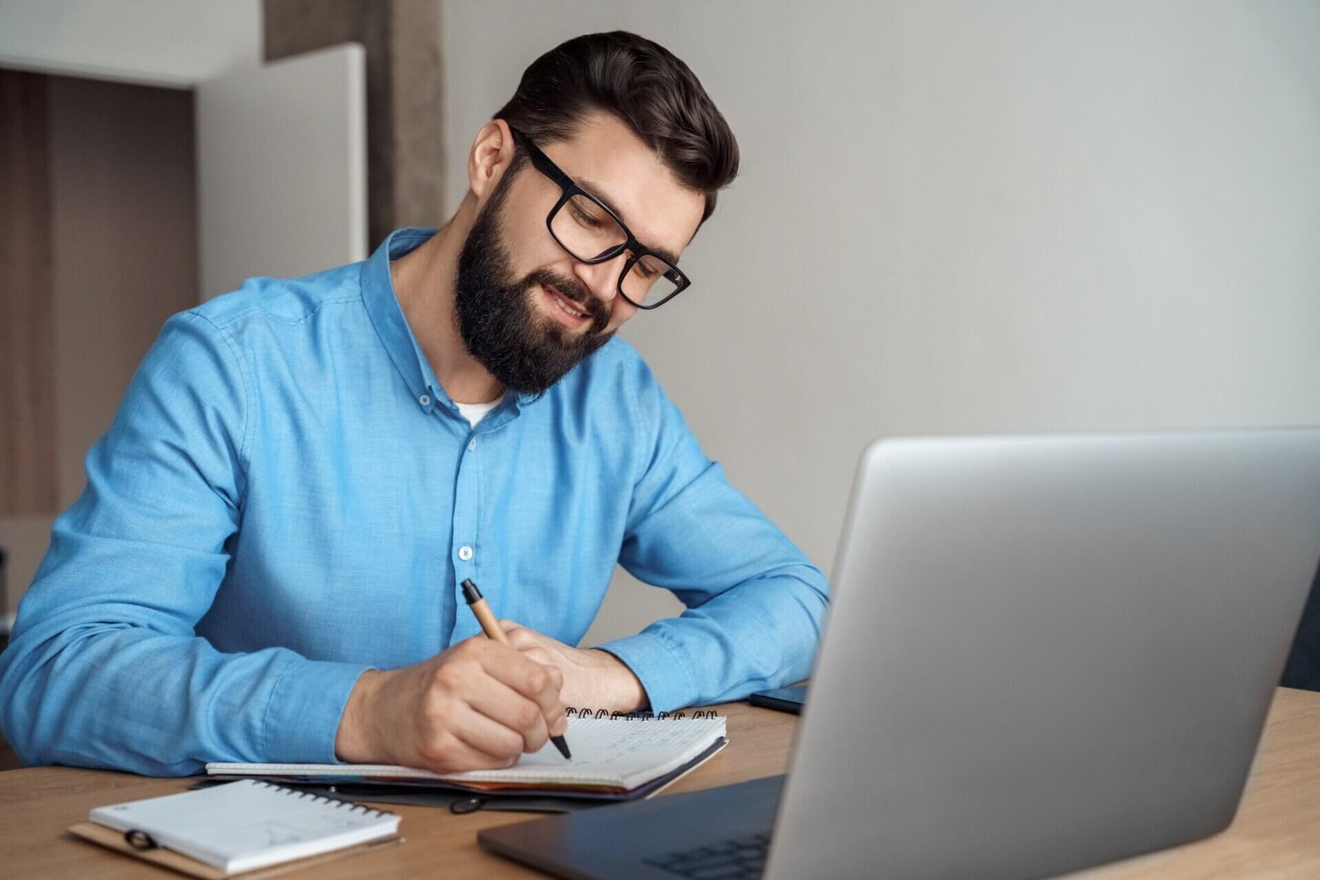 Hombre con gafas toma notas frente al ordenador