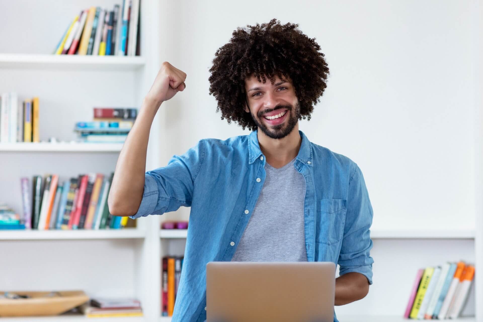 Hombre sonriente levanta brazo mientras trabaja en el ordenador