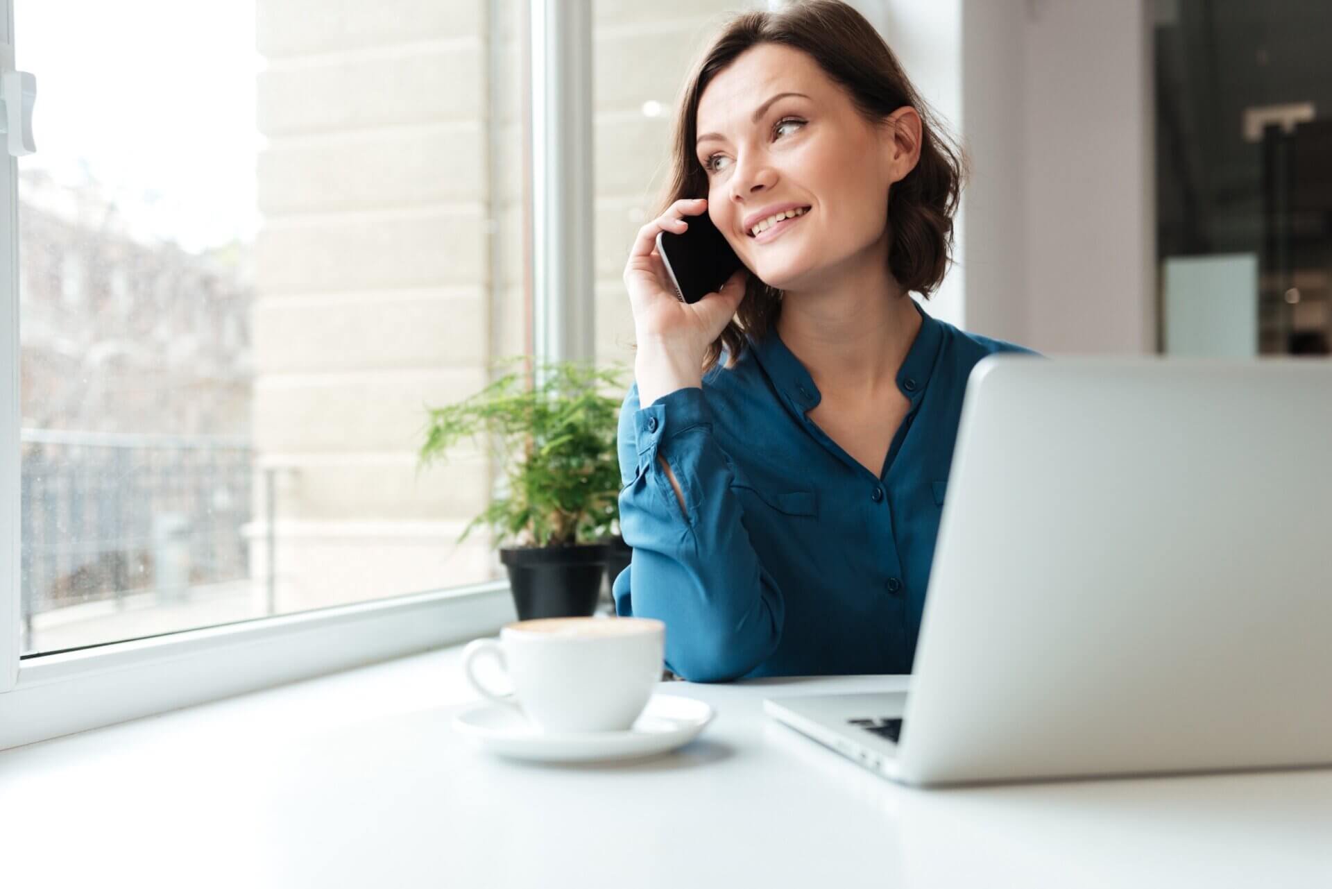 Mujer habla por telefono mientras trabaja ordenador