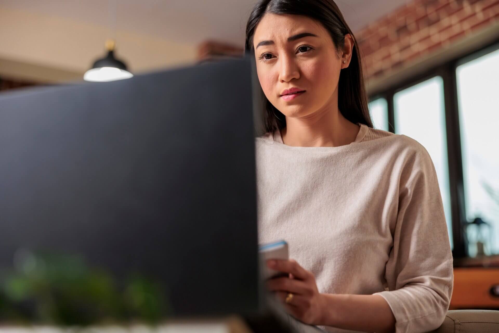 Mujer con expresión preocupada mientras trabaja en el ordenador