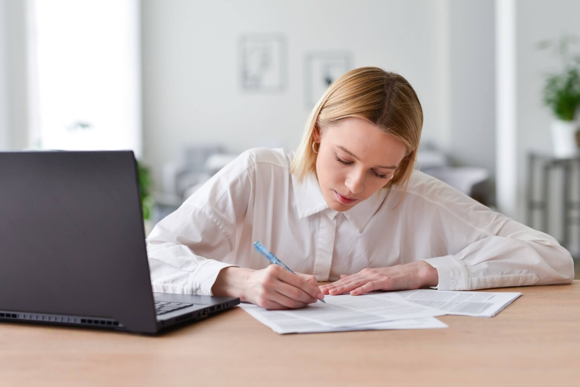 Mujer escribe y revisa documentos en escritorio