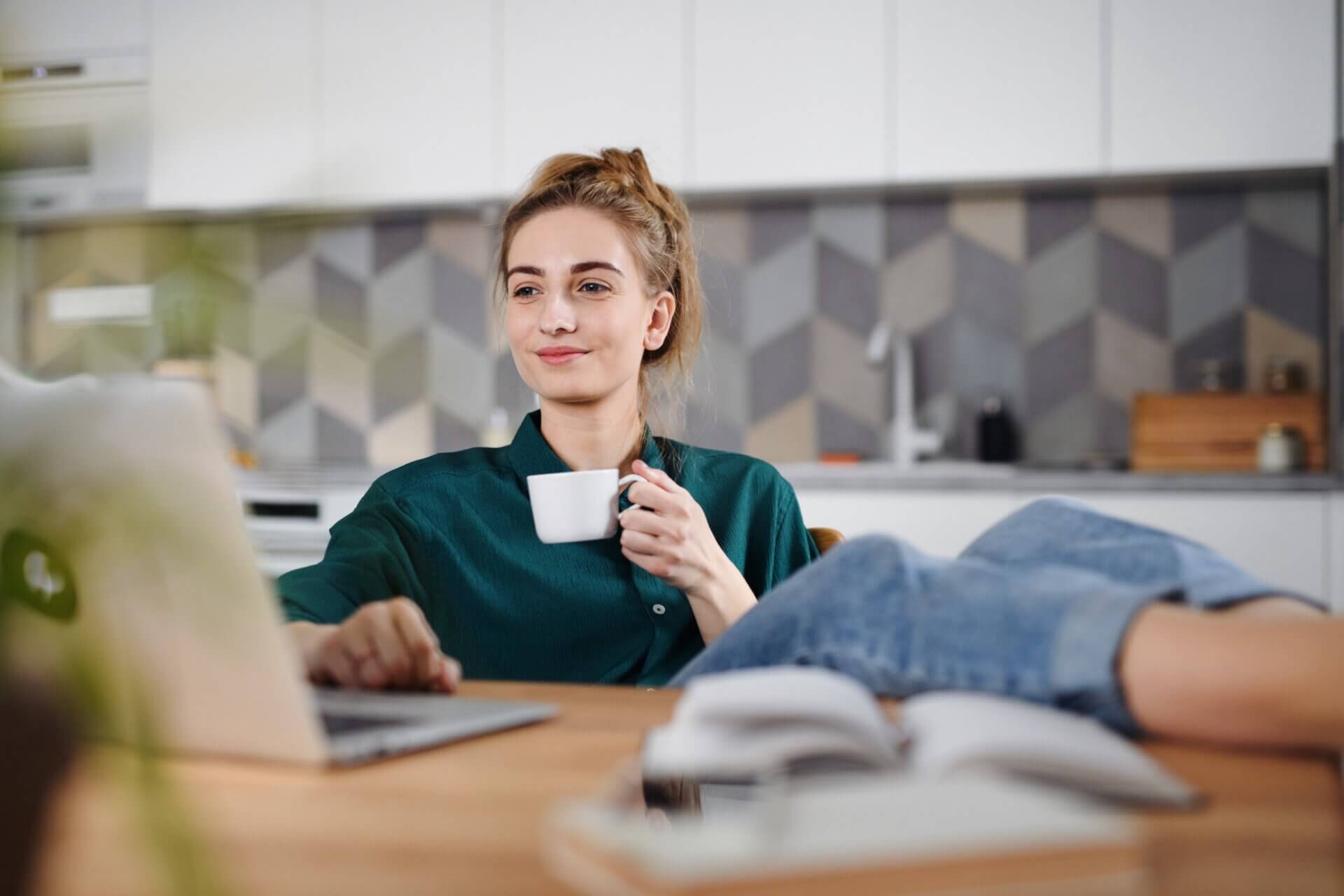 Mujer trabaja ordenador mientras bebe café