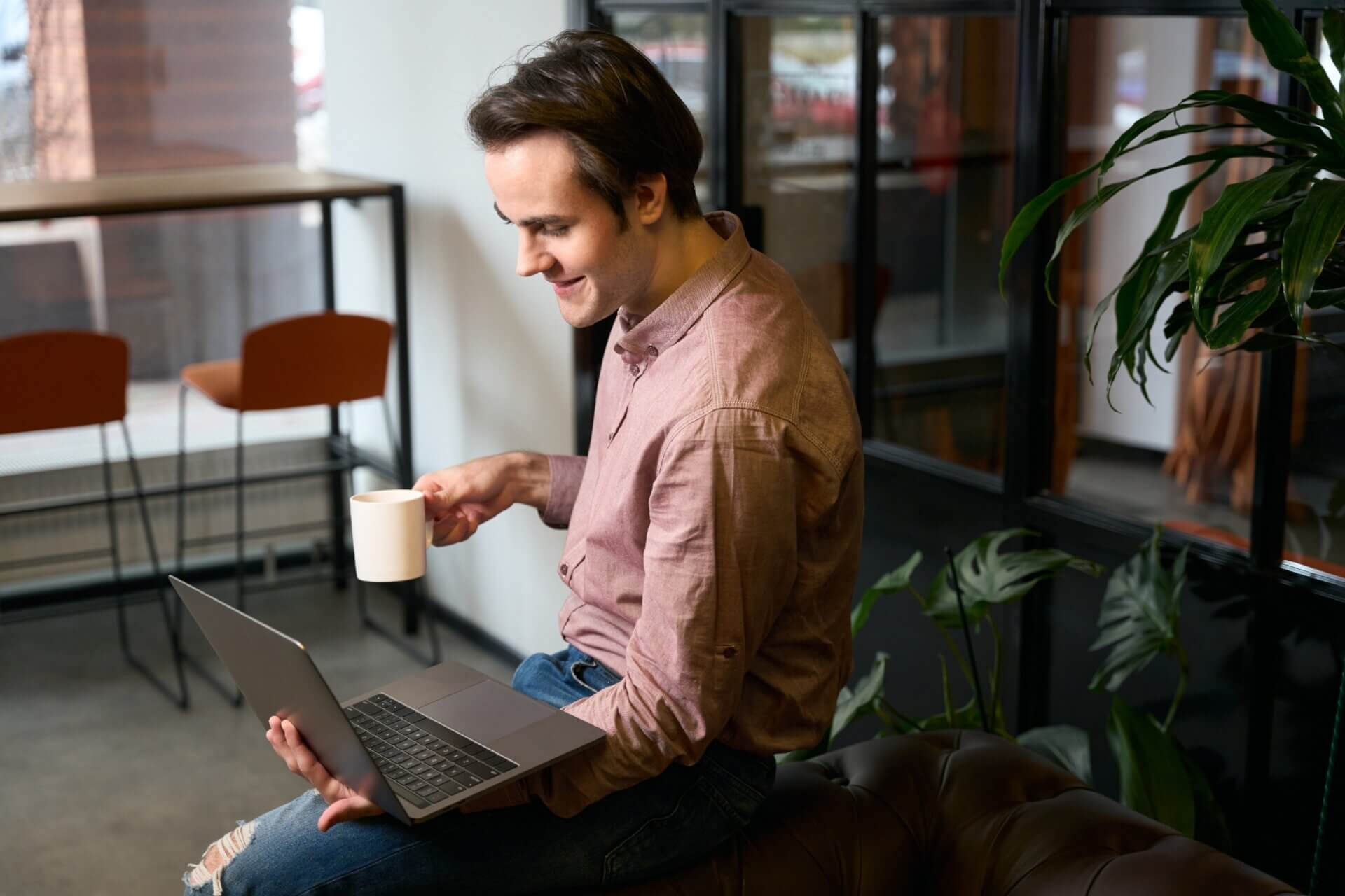 Hombre trabaja en el ordenador mientras bebe café