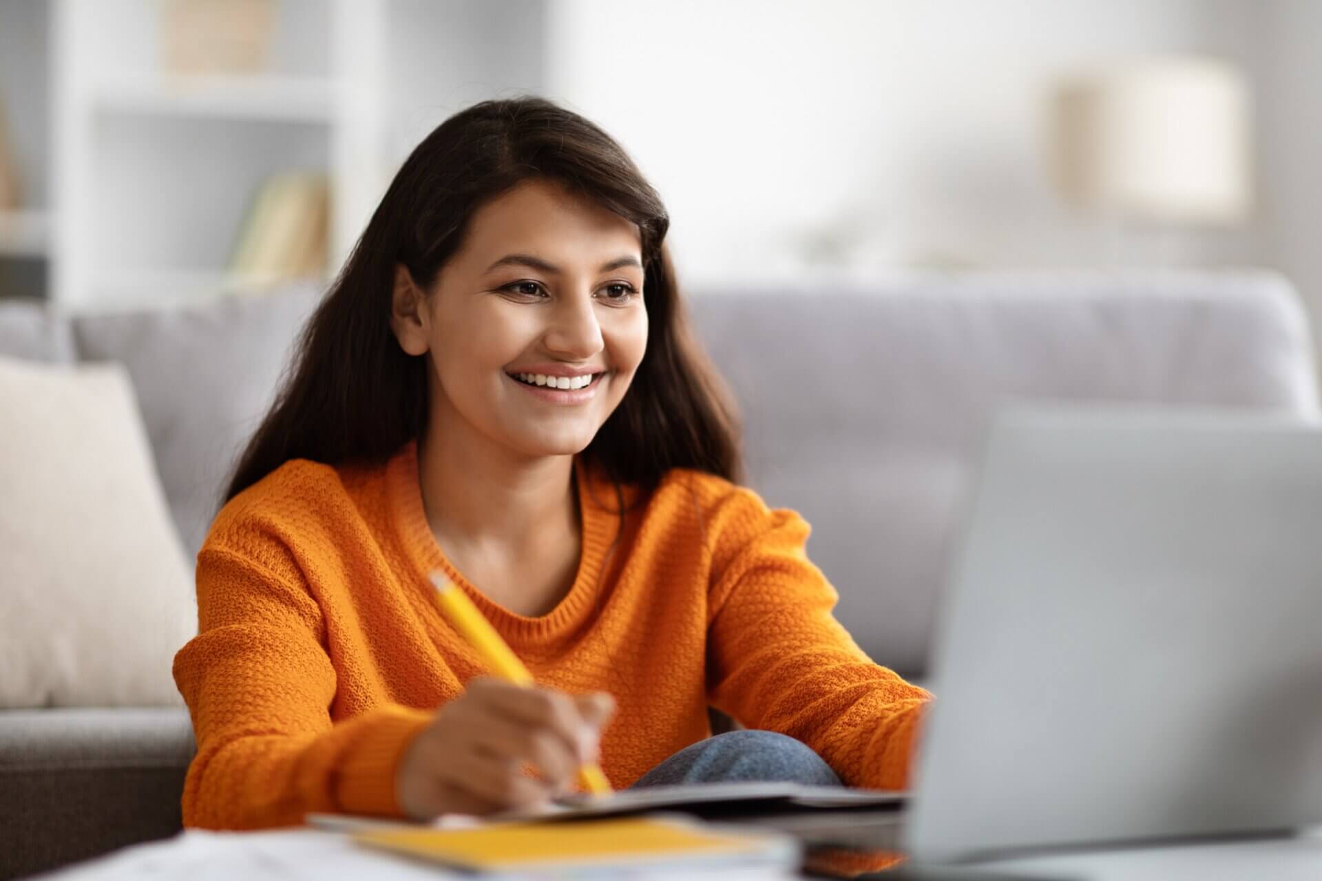 Mujer alegre trabaja con el ordenador en la sala de estar