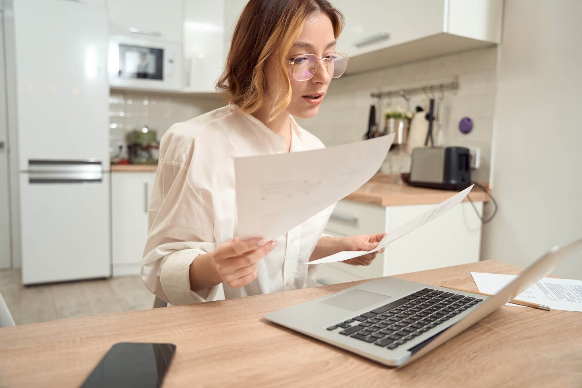 Mujer con gafas trabaja em el ordenador con documentos