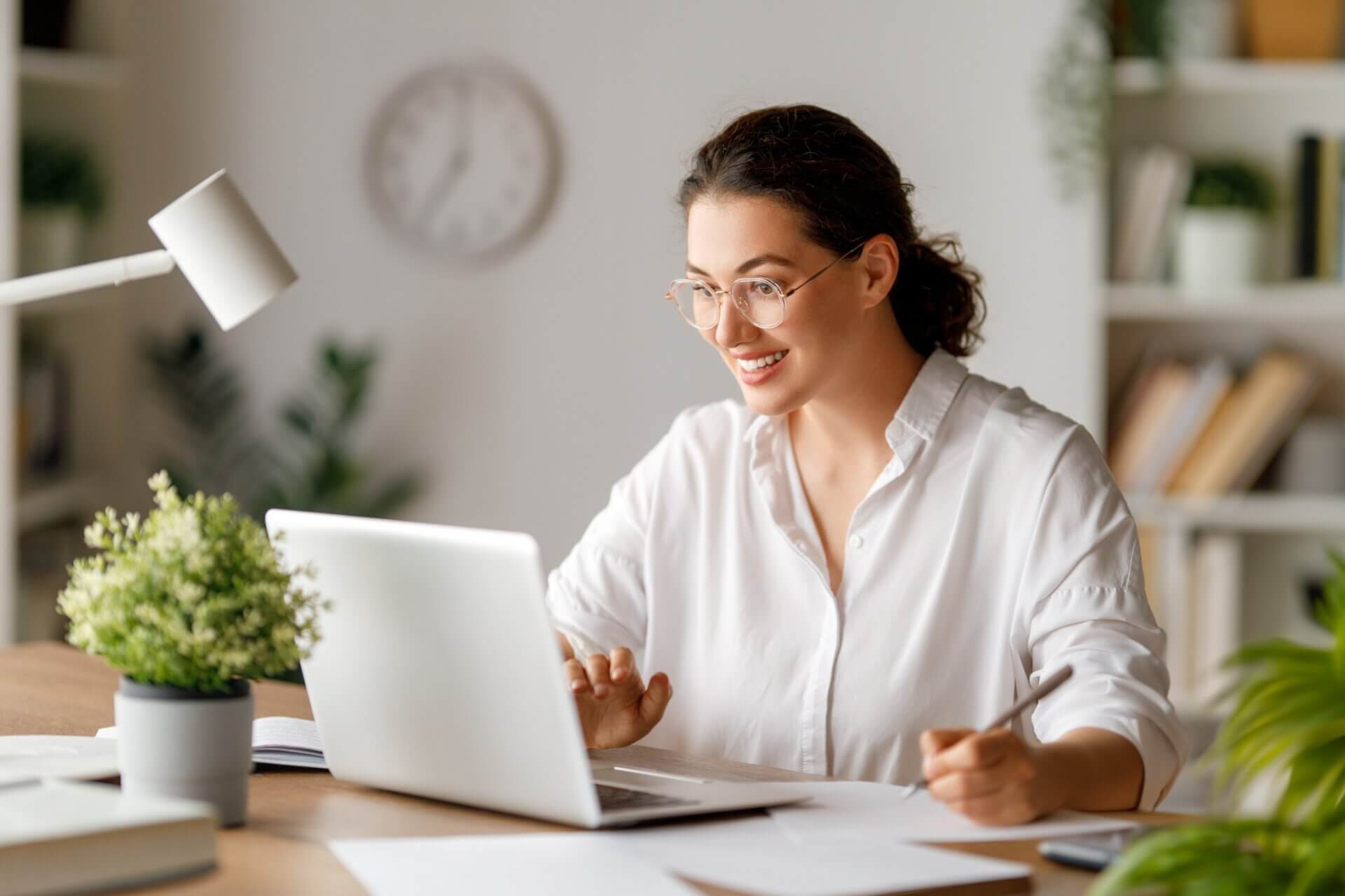 Mujer con gafas sonríe mientras trabaja en el ordenador