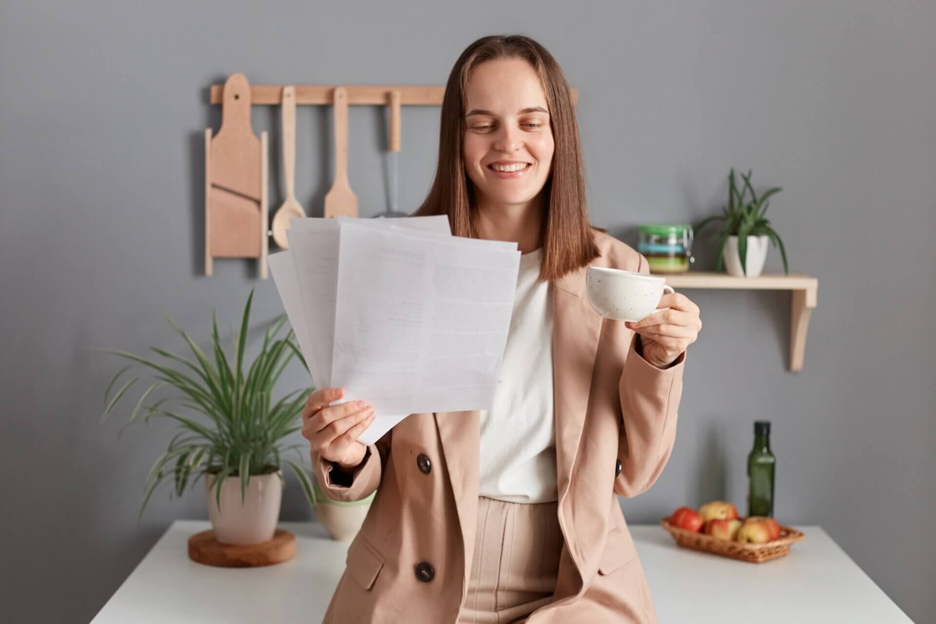 Mujer sonríe mientras lee documentos en la cocina