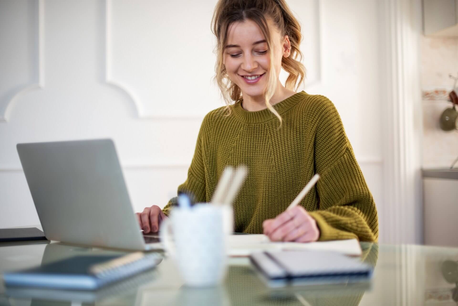 Mujer sonriente toma notas en su escritorio