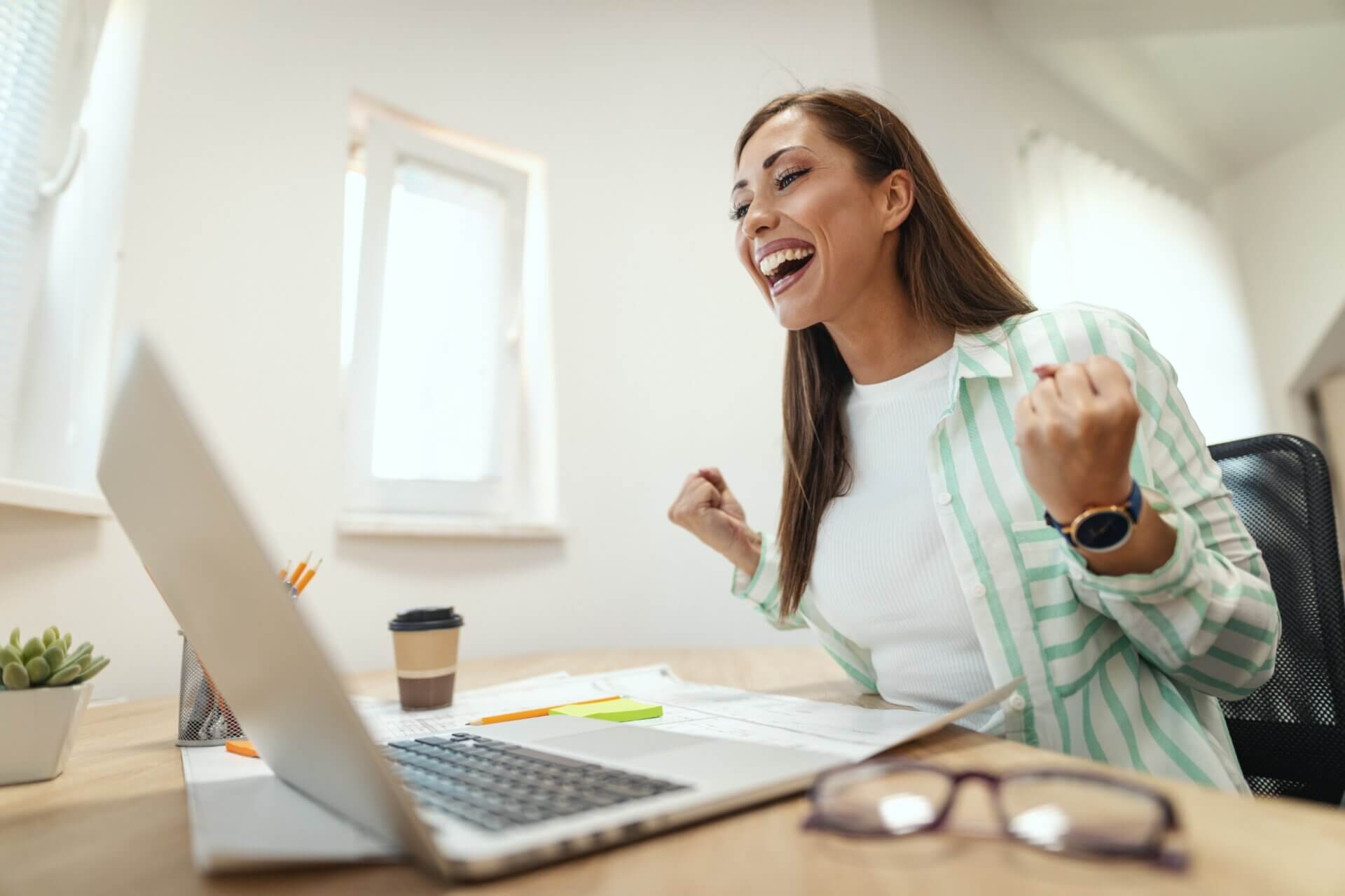 Mujer celebra sonriente frente al ordenador