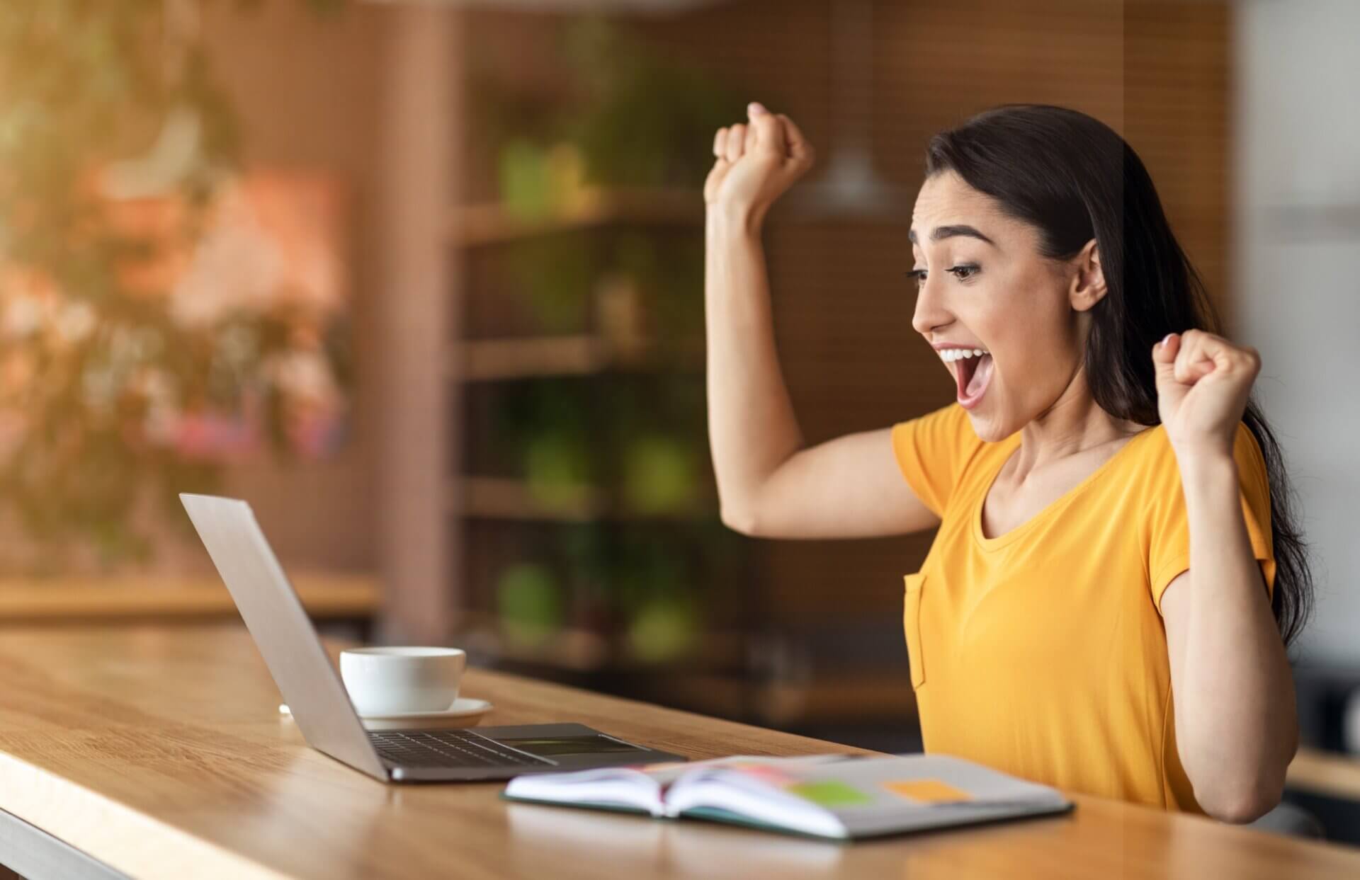 Mujer con camisa amarilla celebra frente al ordenador
