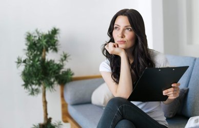 Mujer pensando como hacer un CV para buscar practicas profesionales.